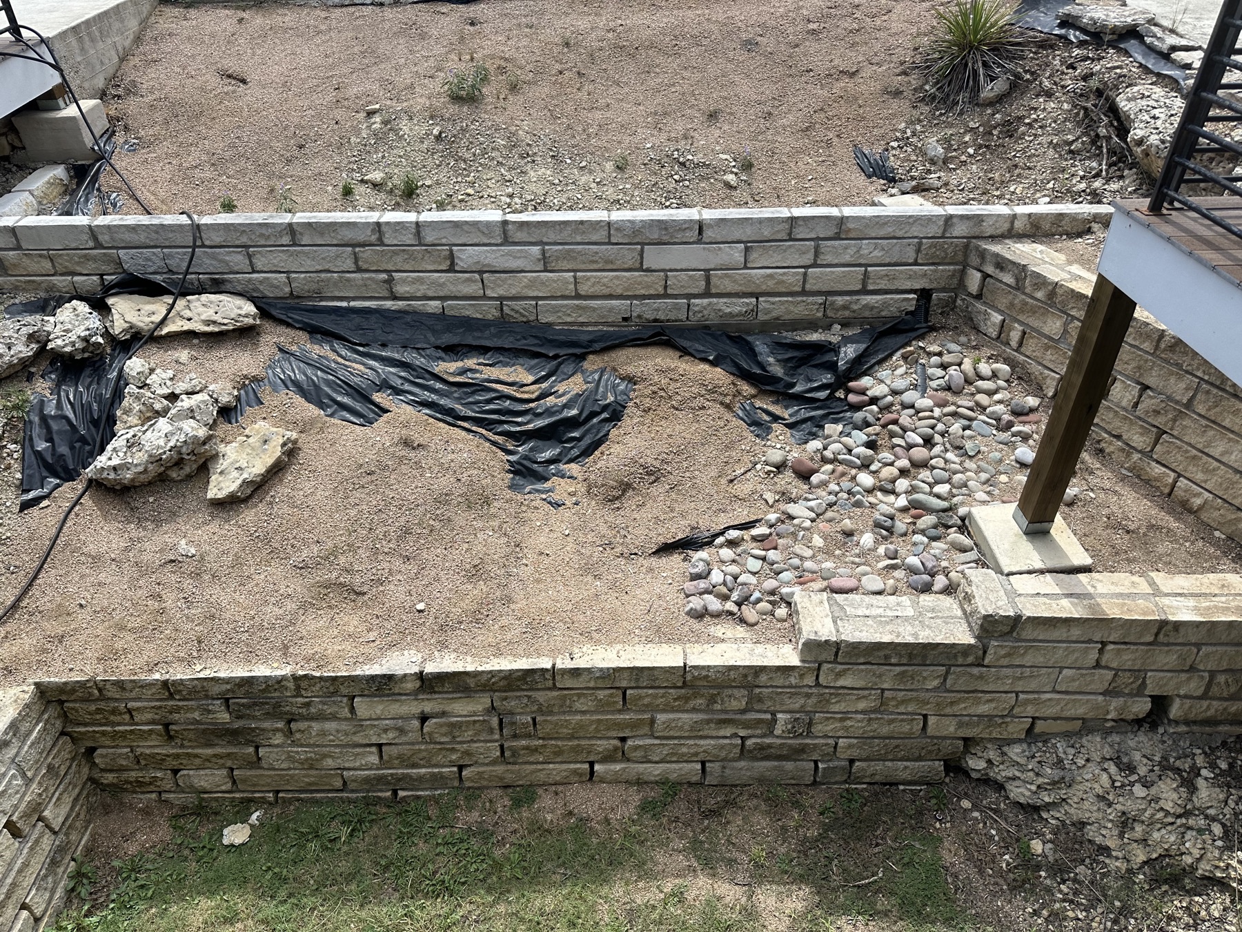 Before: gravel, exposed fabric, and existing stone walls